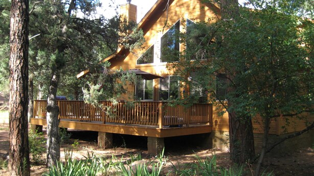 Una cabaña con terraza de madera, rodeada de árboles.