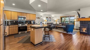 A modern kitchen with wooden cabinets, a central island, and a built-in stove. - Welcome to The Explorers Den, Mountain Harbor #147 (Whitefish)