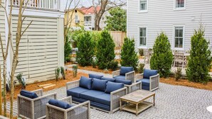 An outdoor patio area with wicker furniture, including sofas and chairs, and a wooden table.