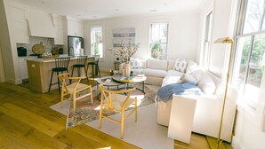 A modern living room with a sofa, chairs, a coffee table, and a kitchen area with cabinets and appliances.