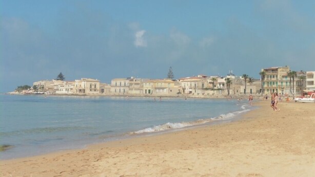 Uma praia com edifícios ao fundo.