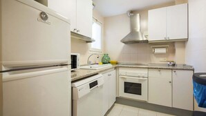 Una cucina con mobili bianchi, forno integrato, microonde, cappa aspirante in acciaio inossidabile e lavello.