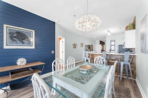 A dining area with a glass table, white chairs, and a wooden bench.