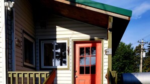A wooden staircase leading to a red door with a window above it.