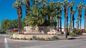 Zona ajardinada con palmeras y un letrero de piedra que dice 'Palm Valley Country Club'.