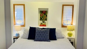 Une chambre à coucher bien aménagée, avec un lit placé au centre de la pièce, flanqué de deux tables de chevet sur lesquelles reposent des lampes et des objets décoratifs.