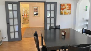 Un coin repas avec une grande table, des chaises et un pot de confiture posé sur la table.