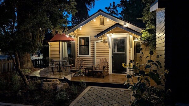Un chalet confortable doté d’une terrasse en bois, de coins salon extérieurs et d’une entrée bien éclairée.