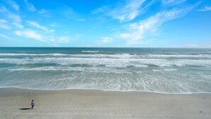 A beach with waves and a clear sky. - Bright oceanfront corner 2/2 with beach/pool views, large balcony, and multiple pools (New Smyrna Beach)