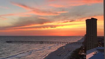 A sunset view from a high-rise building overlooking a beach with a pier extending into the ocean.