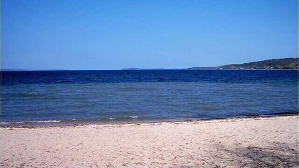 Ein Strand mit klarem, blauem Wasser und einem sandigen Ufer.