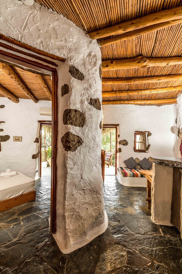 Ein rustikales Interieur mit Steinwänden, Holzbalkendecke und Steinboden.
