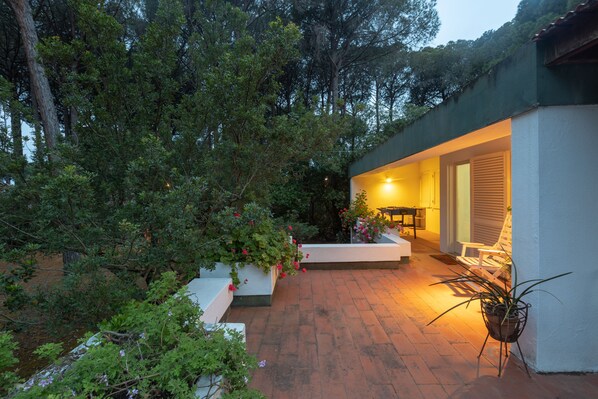 A patio area with a white bench, a table, and potted plants.