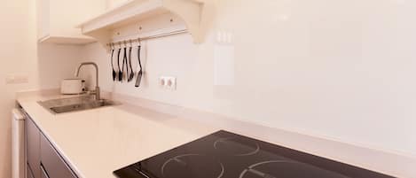 A modern kitchen with a built-in stovetop, a sink, and a small refrigerator.