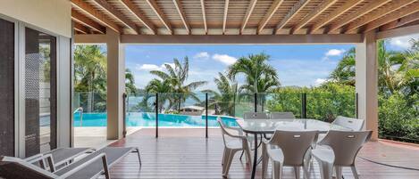 Un'area esterna coperta con piscina, sedie a sdraio e tavolo da pranzo.