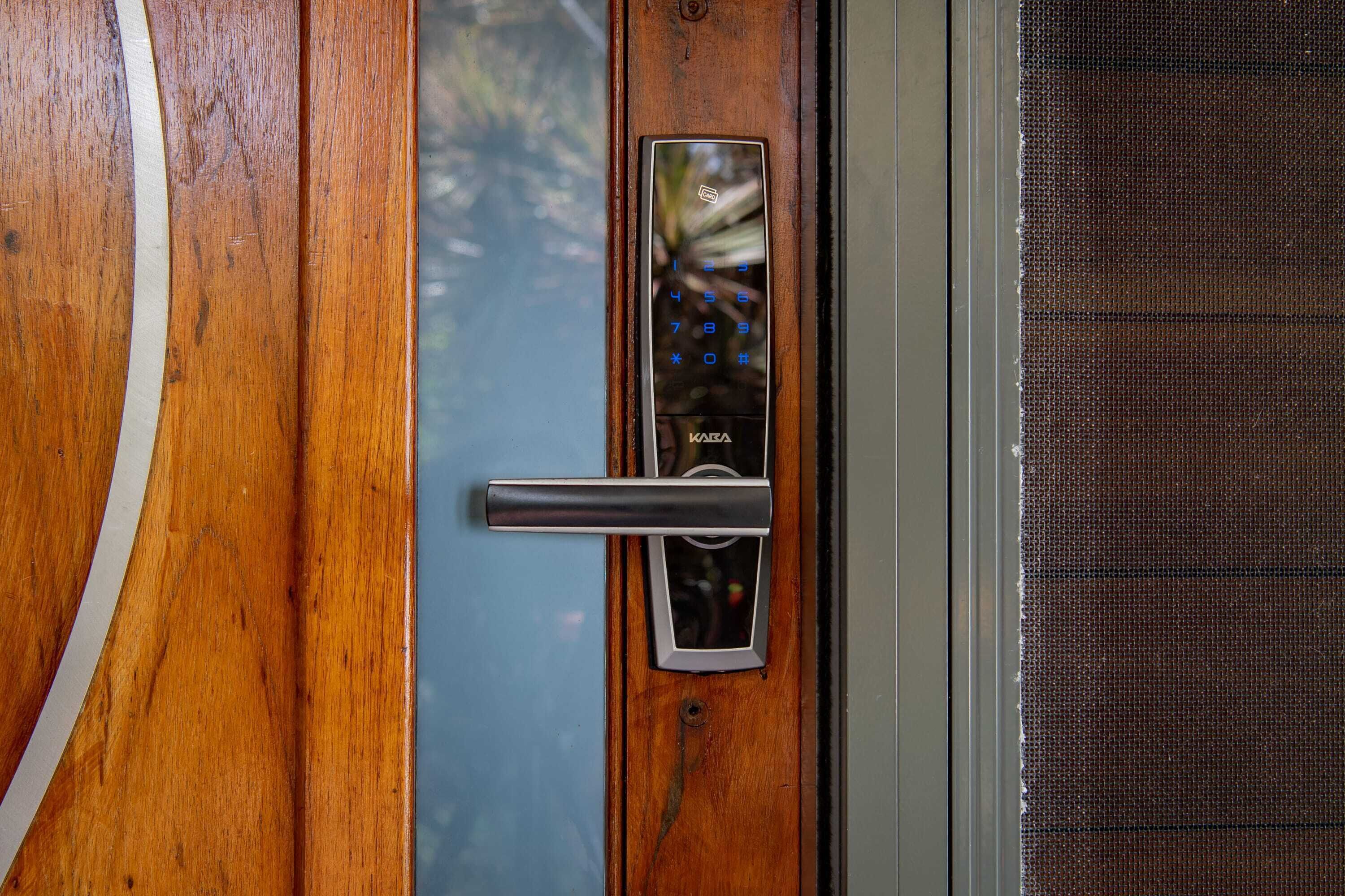 A wooden door with a modern electronic lock and a metal handle.