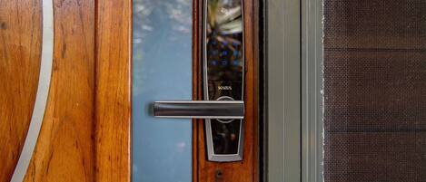 A wooden door with a modern electronic lock and a metal handle.