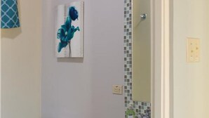 Et badeværelse med toilet, håndvask og et spejl med mosaik bagvæg.