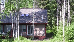 A cabin with a sloped roof, large windows, and a stone foundation near a body of water. - Mountain Harbor Woodland Retreat, Condo 209 (Whitefish)