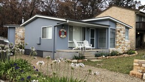 Een modern huis met een gevel van natuursteen, een overdekte veranda met een witte stoel, en een krans aan de muur.