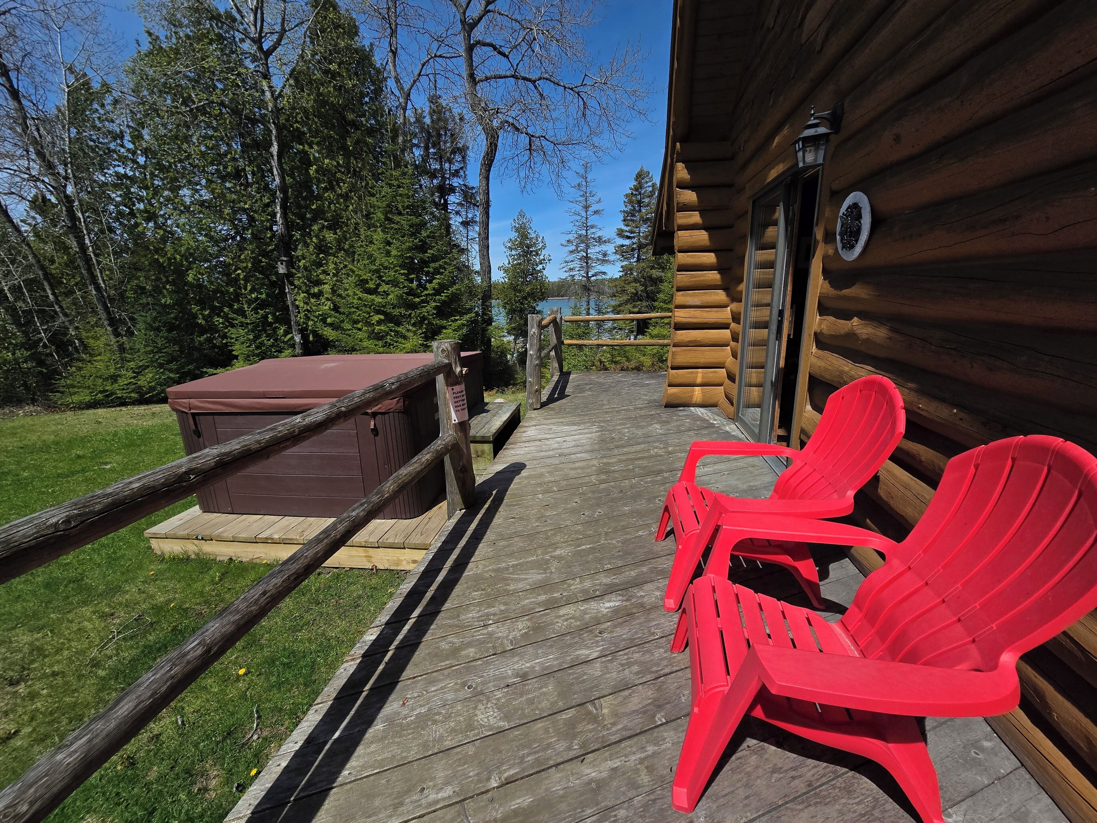 A wooden deck with red chairs and a hot tub.