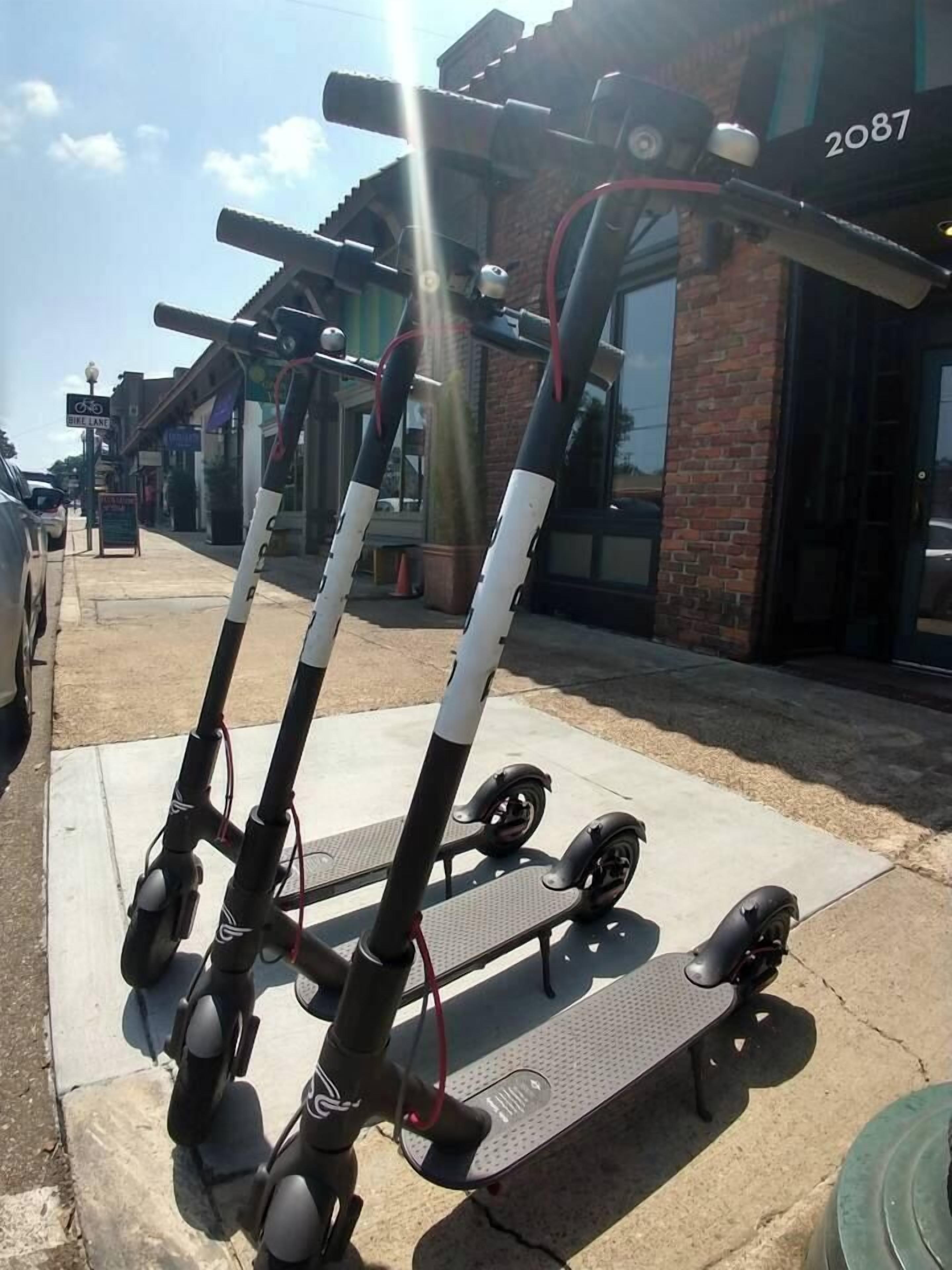 En eldriven tvåsitsig sparkcykel parkerad på en trottoar.