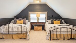 A bedroom with two beds, a window with blinds, a lamp, and a wicker basket.
