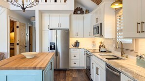 Une cuisine moderne avec des meubles blancs, des appareils en acier inoxydable et un îlot central en bois.