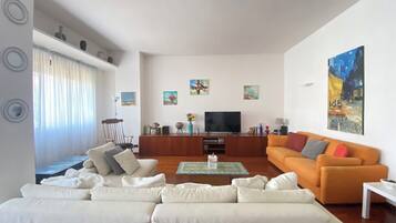 Ein modernes Wohnzimmer mit einer Sofagarnitur, einem Couchtisch, einem Fernseher und Kunstwerken an den Wänden.