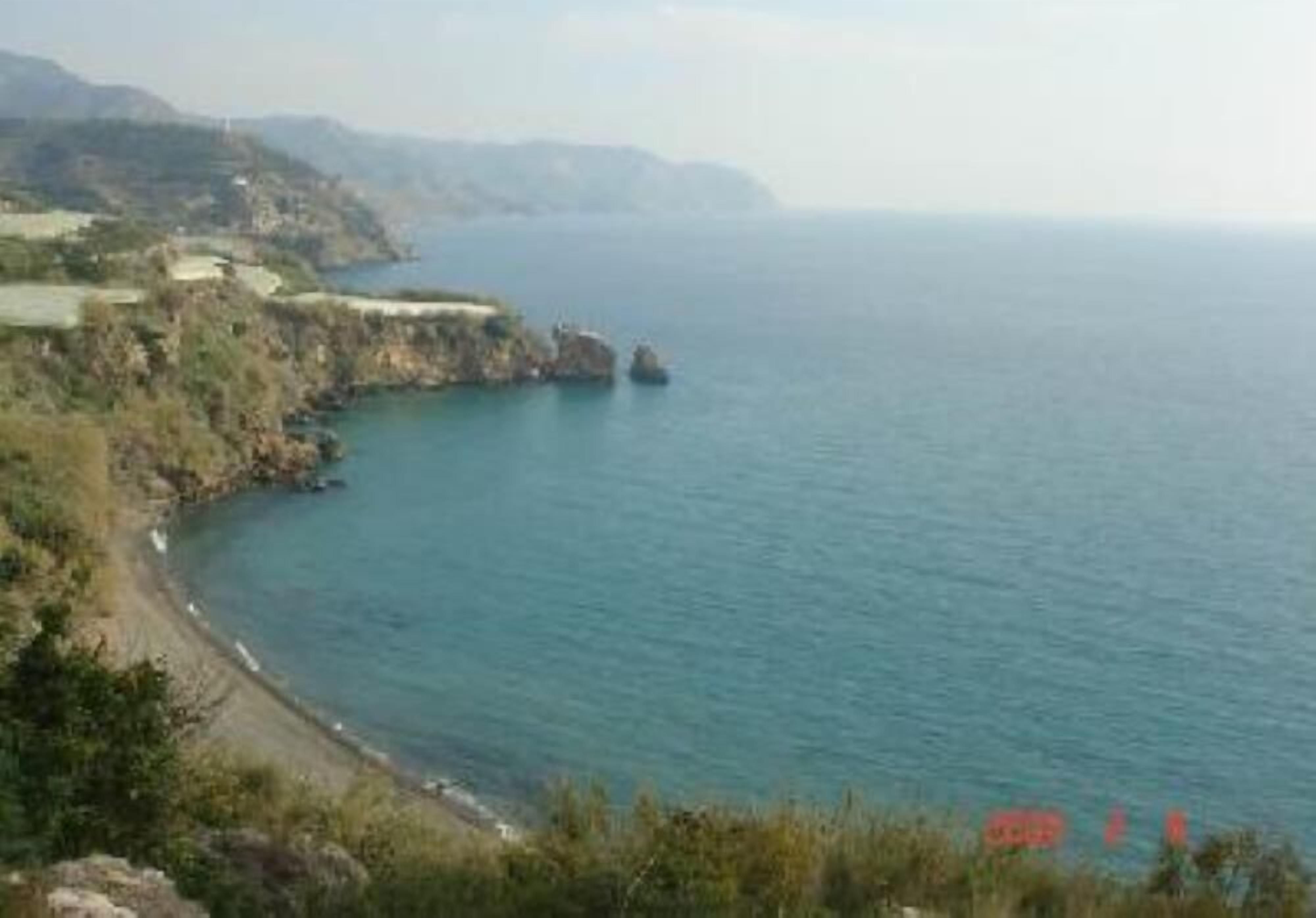 Un paisaje costero con una playa, acantilados rocosos y una vista despejada del mar.