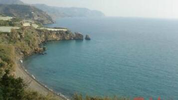 Un paisaje costero con una playa, acantilados rocosos y una vista despejada del mar.