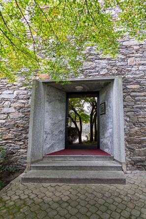 A stone building with a red carpeted entrance and a view of trees through a doorway. - Apartment Castello Ripa Baveno (Baveno VB)