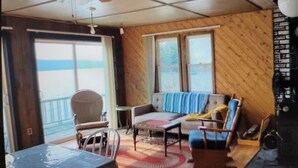 A living room with a sofa, chairs, a coffee table, and a ceiling fan. - Northern Maine Lake Camp (Millinocket)