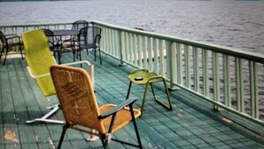 A deck with chairs and tables overlooking a body of water. - Northern Maine Lake Camp (Millinocket)