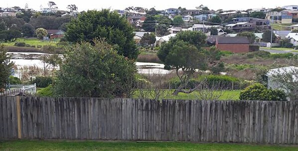 Stroll through a serene neighborhood with a variety of homes, lush greenery, and a tranquil body of water.