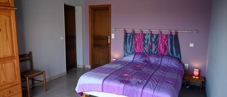 A bedroom with a bed, wooden furniture, and a nightstand with a lamp.