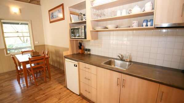 A compact kitchen with wooden cabinets, a built-in microwave, and a sink.
