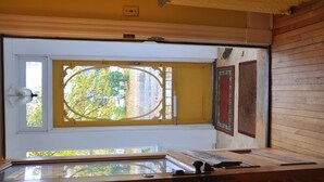 Quarto com uma janela grande, decoração em madeira e uma vitrine de vidro com objetos sobre a mesa.