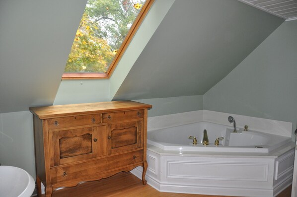 A bathroom with a skylight, a wooden vanity, and a white bathtub.