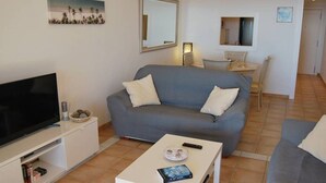 A living room with a grey sofa, a flat-screen TV, a coffee table with a book and remote, and a small table with a lamp. - Costa Blanca, Altea, beautiful apartment with fantastic panoramic views (Altea)