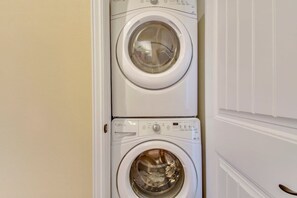 A stacked washer and dryer unit in a room with a white door.