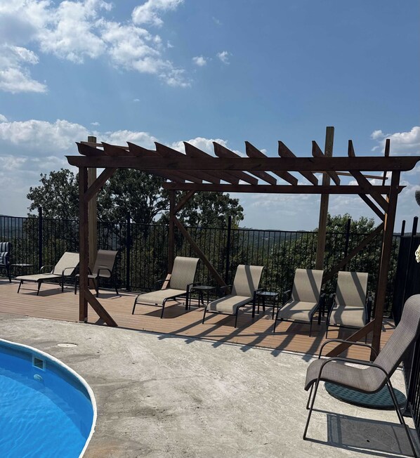 A poolside area with a pergola, lounge chairs, and a swimming pool.
