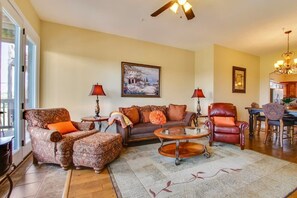 A living room with a sofa, armchair, and coffee table, a painting on the wall, and a chandelier. - 47-3 The Sanctuary Closest to SDC Next Door to Clubhouse w/Indoor/Outdoor Pools & Splashpads (Branson)