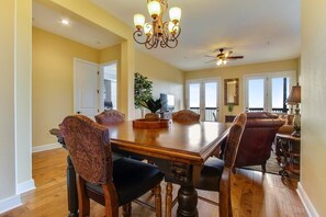 A dining room with a large wooden table, upholstered chairs, and a chandelier.