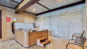 Un jacuzzi con escalones de madera, una silla y un muro de hormigón.