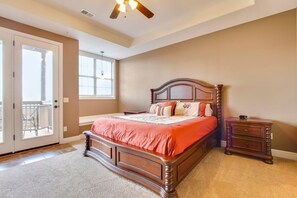A bedroom with a wooden bed, a nightstand, a ceiling fan, a window, and a door leading to a balcony.