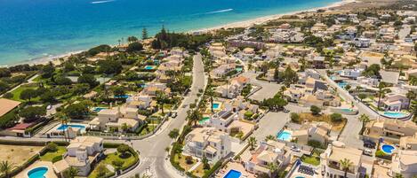 A coastal residential area with houses, roads, and a beach.