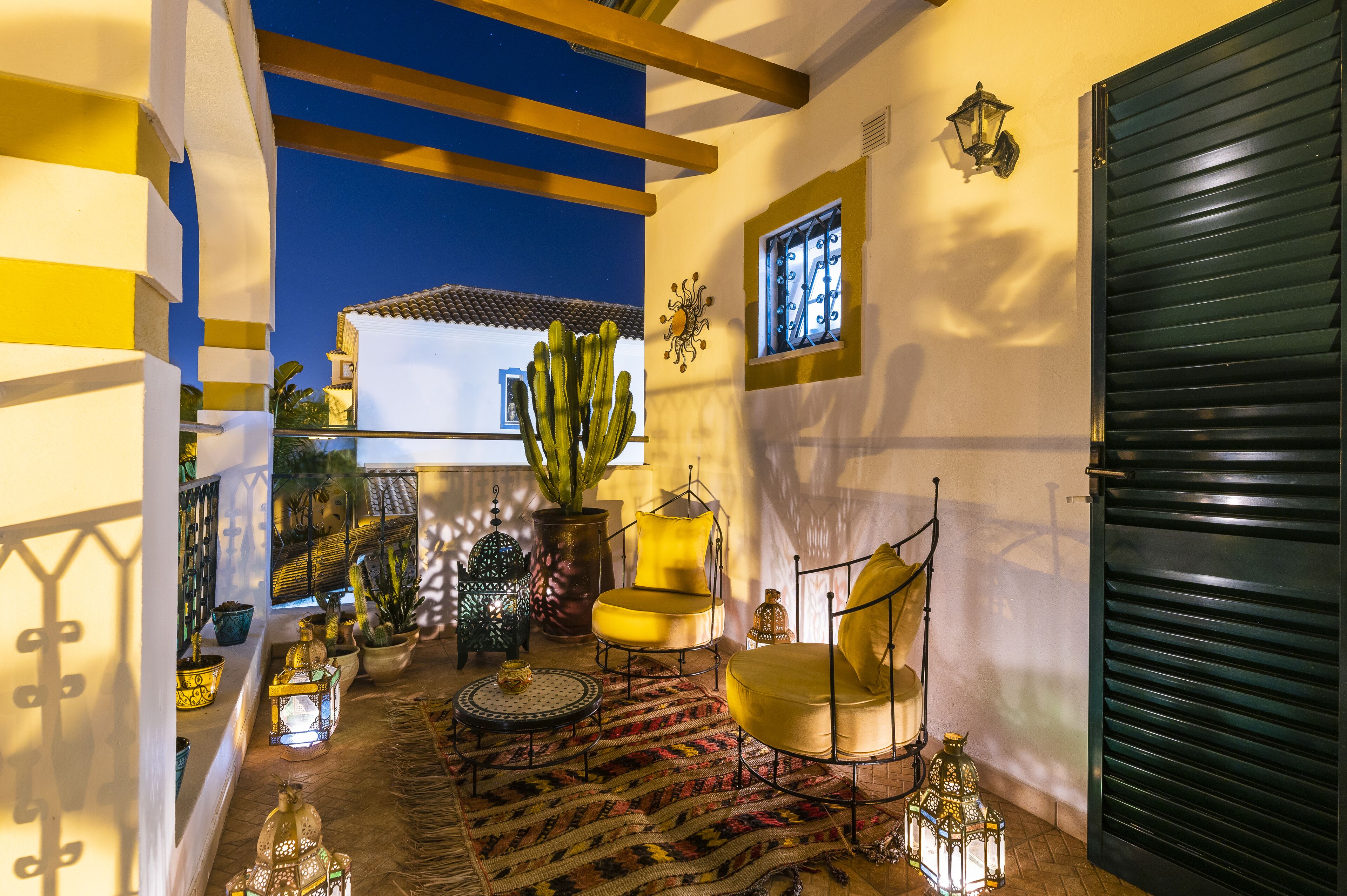 Un interior acogedor con un tapete estampado, un cactus y una silla amarilla.