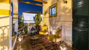A cozy interior with a patterned rug, a cactus, and a yellow chair. - Riad Serpa Galé - Luxury, private pool, AC, wifi and 5 mins from the beach (Albufeira)