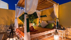 A bed with a canopy, a nightstand with a lantern, and a decorative wall. - Riad Serpa Galé - Luxury, private pool, AC, wifi and 5 mins from the beach (Albufeira)